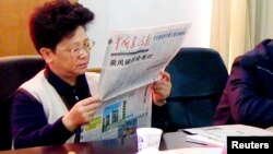 FILE - Yang Xiuzhu reads newspaper during meeting in Wenzhou, Zhejiang province, China, Dec. 29, 2001.