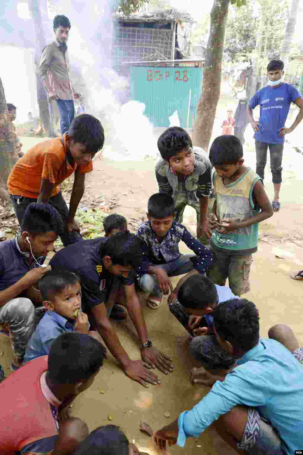 Rohingya refugees spin and flip the coins for a game in Kutupalong camp Mar. 31, 2019. (Hai Do/VOA)