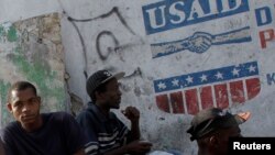 Yon gwoup nèg ki chita dèyè yon mi kote moun kapab wè logo USAID sou mi a. Foto achiv: 13 fevriye 2010. (REUTERS/Ivan Alvarado)