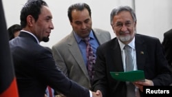 Afghanistan's former Foreign Minister Zalmay Rassoul (R) receives a form to register as a candidate for the presidential election at Afghanistan's Independent Election Commission (IEC) in Kabul October 6, 2013. 