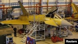 A member of staff works in the cockpit of an aircraft on the Eurofighter Typhoon production line at BAE systems Warton plant near Preston, northern England September 7, 2012.