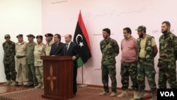 Pemimpin Pemerintah Transisi Libya (NTC) Mustafa Abdel Jalil (tengah) berdiri di antara Tentara Nasional (kiri) dan Pejuang Anti Gaddafi (kanan) dalam sebuah jumpa pers di Benghazi (24/10).