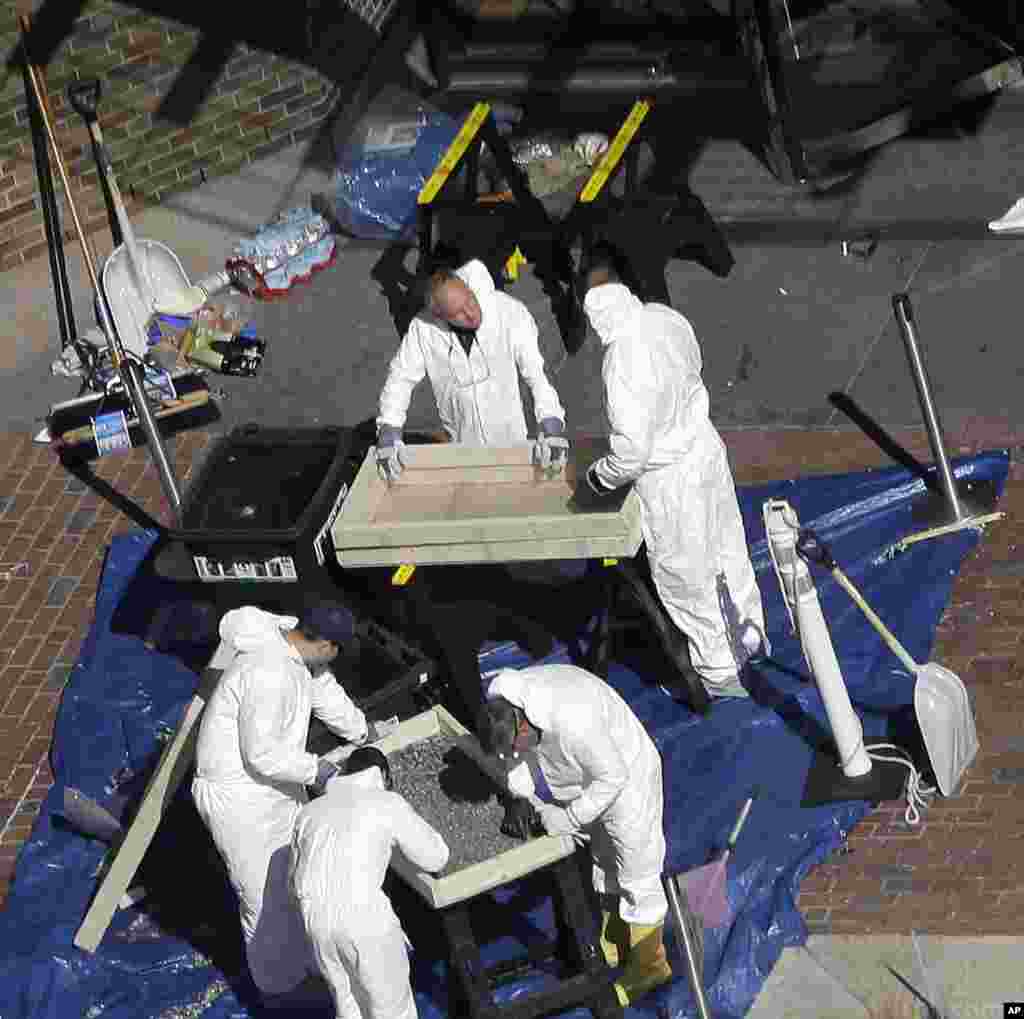 Investigators inspect the area between the two blast sites near the Boston Marathon finish line, Thursday, April 18, 2013, in Boston. Boston remained under a heavy security presence, with scores of National Guard troops gathering among armored Humvees in 