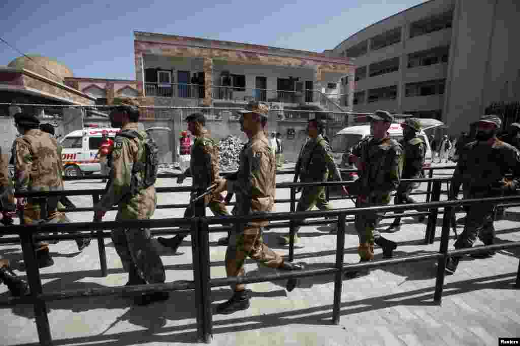 Pakistani soldiers march toward the site of a suicide bomb blast in a judicial compound in Peshawar, March 18, 2013.