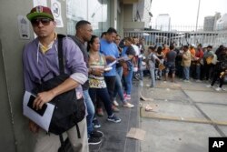 FILE - Venezuelan citizens stand in a line outside the Foreign Ministry office in Lima, Peru, Jan. 23, 2018.