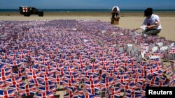 FILE - Royal British Legion volunteers plant some of the 22,000 Union Jack flags, each adorned with a picture of a poppy and, some with hand-written notes of gratitude to Allied soldiers, on the beach in Asnelles, Normandy, France, June 6, 2014.