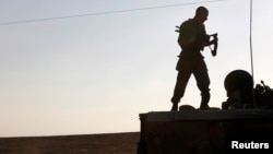 Binh sĩ Israel đứng trên xe bọc thép gần biên giới dải Gaza. 