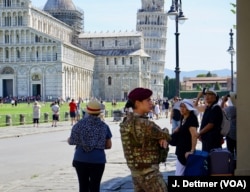 Female soldier standing guard at the Leaning Tower of Pisa, the 14th century bell tower, and its cathedral. Automatic bollards on the access roads to the cathedral square can be raised at a flick of a switch.