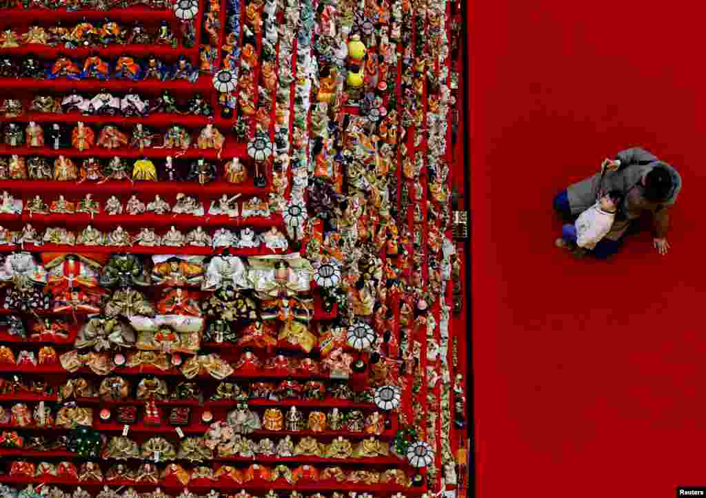 A woman and her daughter look at a showcase featuring 1,605 traditional Japanese dolls at an event celebrating Hinamatsuri, a traditional festival dedicated to the healthy growth of girls, in Konosu, Saitama Prefecture.