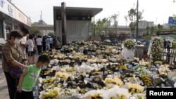 People stand next to flowers placed at an entrance to a subway station of Metro Line 5 in memory of flood victims following heavy rainfall in Zhengzhou, Henan province, China July 27, 2021. Picture taken July 27, 2021. China Daily via REUTERS ATTENTION E