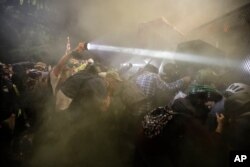 Demonstrators push on a fence as tear gas is deployed during a Black Lives Matter protest at the Mark O. Hatfield United States Courthouse, July 25, 2020, in Portland, Ore.