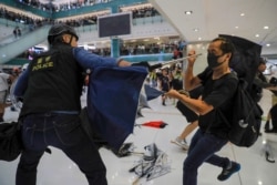 A policeman scuffles with a protester inside a mall in Sha Tin District in Hong Kong, July 14, 2019.