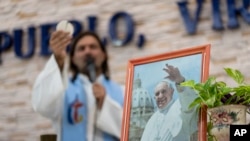 Una fotografía del Papa Francisco frente al sacerdote Nicolás Angelotti mientras dirige una misa para orar por la salud del Papa en Buenos Aires, Argentina, el 18 de febrero de 2025.