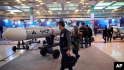 FILE - Visitors look at a cruise missile at a military hardware exhibit, at Imam Khomeini Grand Mosque, in Tehran, Iran, Feb. 3, 2019.