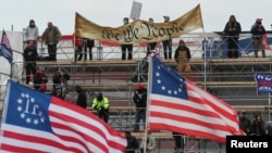 Supporters of U.S. President Donald Trump hold a "We the People" banner, a Three Percenters flag and a 13-star Betsy Ross U.S. flag, gather in front of the U.S. Capitol Building in Washington, Jan. 6, 2021. 