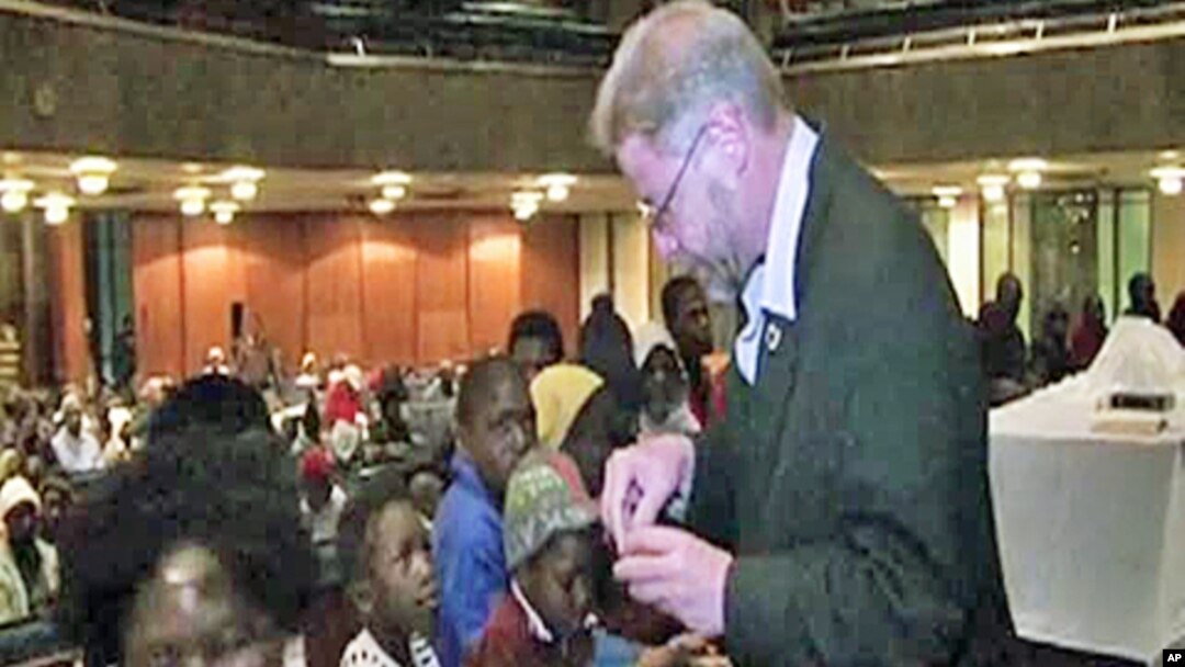 Bishop Paul Verryn offers a blessing to his parishioners in a dimly-lit downtown Johannesburg church