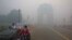  FILE - A man covers his face as he rides in front of the landmark India Gate, enveloped by smoke and smog, in New Delhi, India, Oct. 31, 2016.