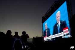 Warga menonton debat antara Presiden Donald Trump, di sebelah kiri layar video, dan calon presiden dari Partai Demokrat, mantan Wakil Presiden Joe Biden, berbicara dalam Presidential Debate Watch Party di Fort Mason Center di San Francisco, 22 Oktober 2020. (Foto: AP )