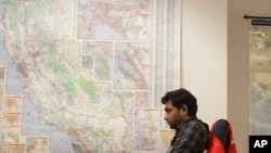 FILE - A senior program analyst works next to a map of California in the Pacific Gas and Electric (PG&E) Emergency Operations Center in San Francisco, Oct. 10, 2019.