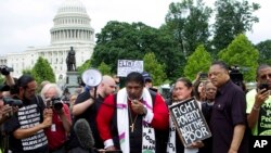 FILE - Rev. Dr. William Barber II, accompanied by Rev. Dr. Liz Theoharis and Rev. Jesse Jackson, speaks to the crowd outside of the U.S. Capitol during a Poor People's Campaign rally at The National Mall in Washington, June 23, 2018.