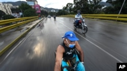 Manuel Mendoza viaja en su silla de ruedas agarrándose a la parte trasera de una motocicleta en el barrio La Paz de Caracas, el 9 de noviembre de 2020.