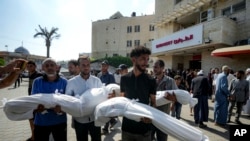 Warga Palestina mebawa jenazah kerabat mereka yang tewas terbunuh dalam serangan Israel di Deir al-Balah, pada 13 Juli 2024. (Foto: AP/Abdel Kareem Hana)