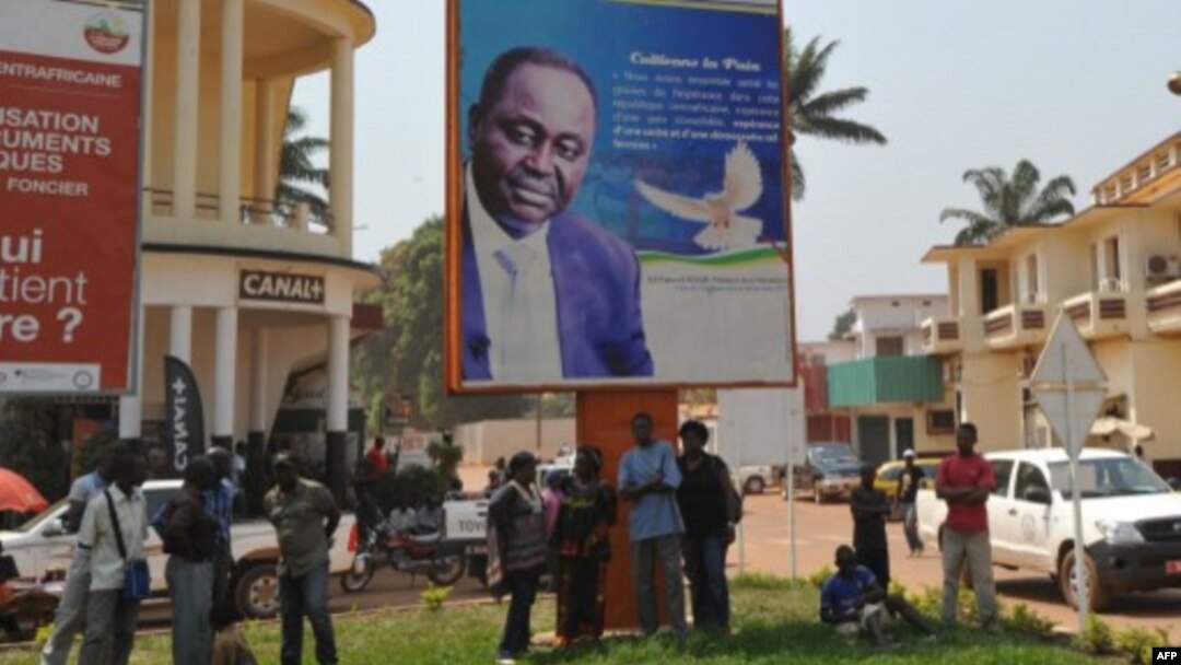People stand under the poster of Central Africa Republic's President Francois Bozize in Bangui on December 28, 2012