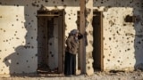 A Syrian Kurdish woman, fleeing from north of Aleppo, stands leaning on a bullet-riddled wall upon arriving in Tabqa, on the western outskirts of Raqa, Dec. 4, 2024.