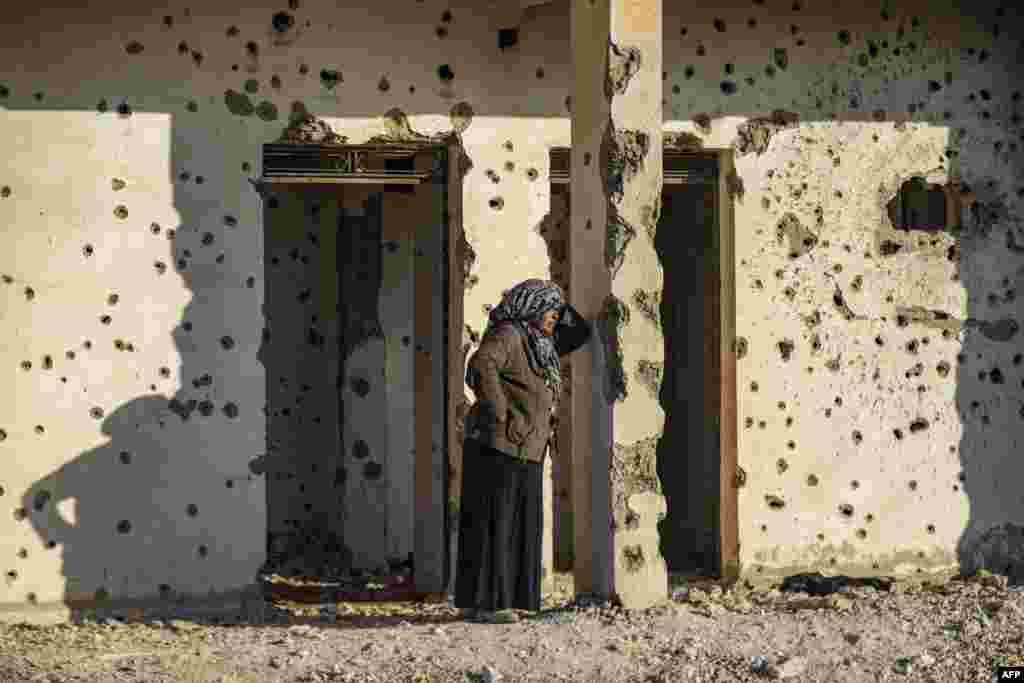 Seorang wanita Kurdi Suriah, yang melarikan diri dari kota Aleppo, berdiri dekat dinding yang penuh dengan lubang tembakan saat tiba di Tabqa, di pinggiran barat kota Raqa. (AFP)&nbsp;