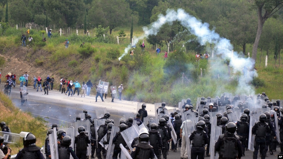 Policías antimotines lanzan gas lacrimógeno a estudiantes y manifestantes de la escuela de Ayotzinapa, para bloquearles el paso hacia Chilpancingo.