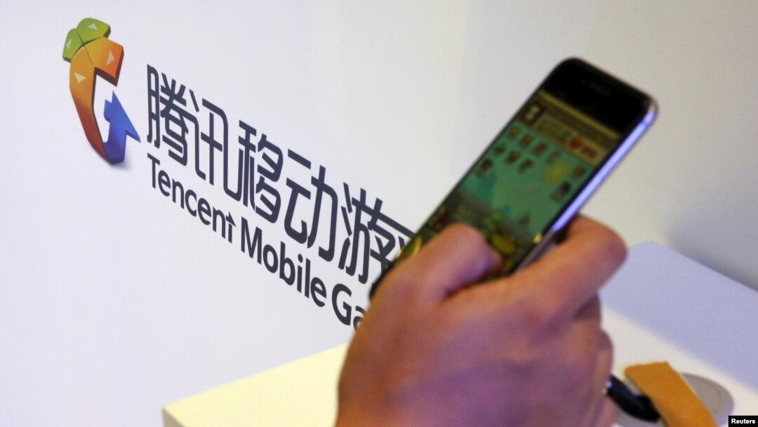 在北京舉行的全球移動互聯網會議上一名參觀者在騰訊展台前玩智能手機上的遊戲。 （2015年4月28日）