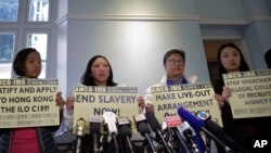 Mantan pembantu rumah tangga Indonesia di Hong Kong, Erwiana Sulistyaningsih (dua dari kiri) dan pendukungnya memegang plakat pada sebuah konferensi pers di Hong Kong, Jumat, 22 Desember 2017.