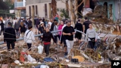 Los residentes caminan por una calle después de las inundaciones en Paiporta, cerca de Valencia, España, el miércoles 30 de octubre de 2024. (Foto AP/Alberto Saíz).