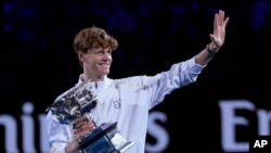 Jannik Sinner of Italy waves as he carries the Norman Brookes Challenge Cup after defeating Alexander Zverev of Germany in the men's singles final at the Australian Open tennis championship in Melbourne, Jan. 26, 2025.