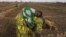 FILE - A woman, with a child on her back, is seen planting beans on a farm in Heremakono, Mali.