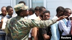 Yon sòlda kap mete lòd nan liy kote plizyè moun vin enskri pou antre nan nouvèl fòs zame Ayiti a nan Gresye, Ayiti 18 Jiyè, 2017. (Foto: Reuters/Jeanty Junior Augustin)