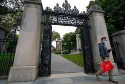 FILE - A passer-by departs a gate to the campus of Brown University, in Providence, R.I., Oct. 12, 2020. Brown has suspended in-person instruction due to the COVID-19 pandemic.