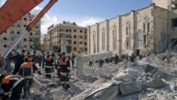 Syrian workers inspect the site of an explosion outside a military security building, one of two sites of bomb blasts in Syria's northern city of Aleppo.