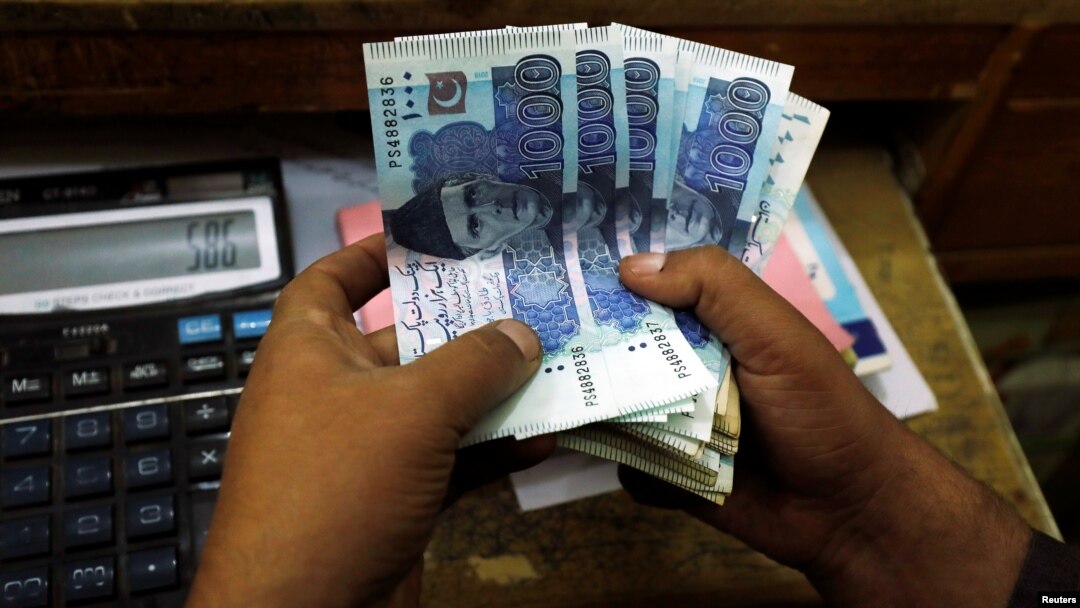 FILE - A trader counts Pakistani rupee notes at a currency exchange booth in Peshawar, Dec. 3, 2018. 