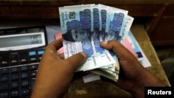 FILE - A trader counts Pakistani rupee notes at a currency exchange booth in Peshawar, Dec. 3, 2018. 