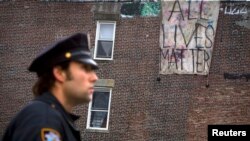 Un oficial de policía frente a un cartel que dice "Todas las vidas importan" en Brooklyn.