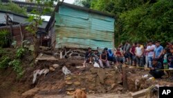 Neighbors watch firefighters search for survivors where homes were swept away overnight by a swollen Naranjo River after heavy rain in the "Dios es fiel," or "God is Loyal" shanty on the outskirts of Guatemala City, Sept. 25, 2023.