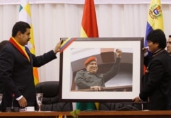 El presidente de Venezuela, Nicolás Maduro, a la izquierda, le entrega una fotografía del difunto presidente Hugo Chávez al presidente de Bolivia, Evo Morales, en una reunión en Cochabamba, Bolivia. Mayo 25, 2013. Foto: AP.