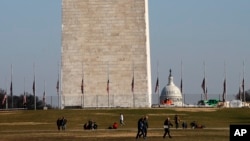 People walk near the Washington Monument, with the U.S. Capitol in the background, Dec. 26, 2018, as the partial government shutdown continues in Washington. A shutdown affecting parts of the federal government threatens to carry over into January.