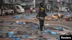 A protester walks in a street full of water bags to be used against tear gas, during an anti-coup protest at Hledan junction in Yangon, Myanmar, March 14, 2021.