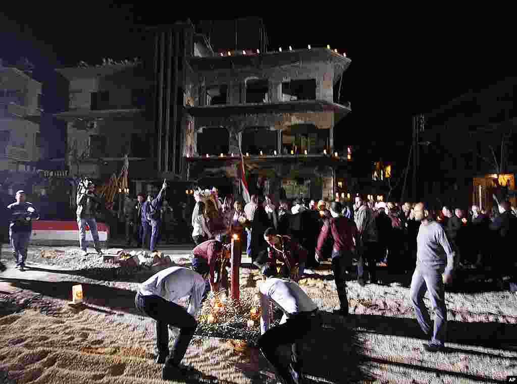 Syrian scouts place a candle during a vigil after a mass prayer for civilians and security officers killed in Saturday explosions in Damascus. (AP) 