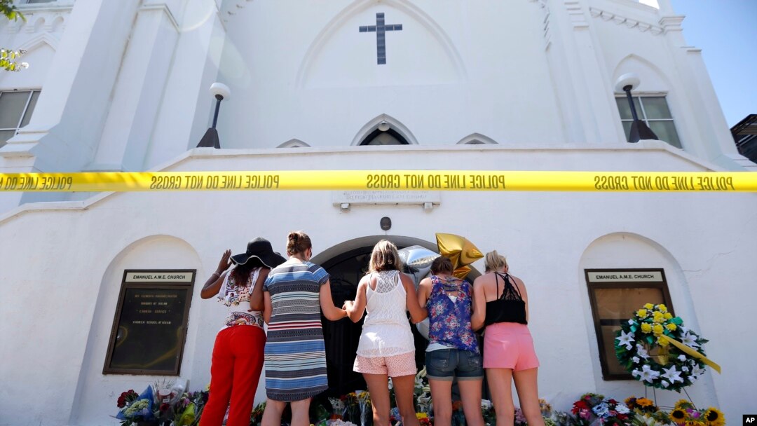 FILE - A group of women pray together at a makeshift memorial on the sidewalk in front of the Emanuel AME Church, in Charleston, S.C., June 18, 2015. Dylann Roof shot a killed nine people in a bible study at the church. 
