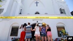 FILE - A group of women pray together at a makeshift memorial on the sidewalk in front of the Emanuel AME Church, in Charleston, S.C., June 18, 2015. Dylann Roof shot a killed nine people in a bible study at the church. 