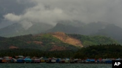 A nickel mine is visible on top of a hill above a village on Kabaena Island, Indonesia, Thursday, Nov. 14, 2024. (AP Photo/Yusuf Wahil)