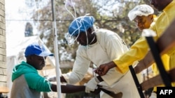 Une infirmière prend soin d'un patient atteint de choléra lors d'une visite du ministre de la Santé du Zimbabwe, au centre de traitement du choléra de l'hôpital Beatrice, à Harare, le 11 septembre 2018.